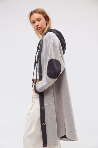 Woman wearing a long gray cardigan with black accents on a white background