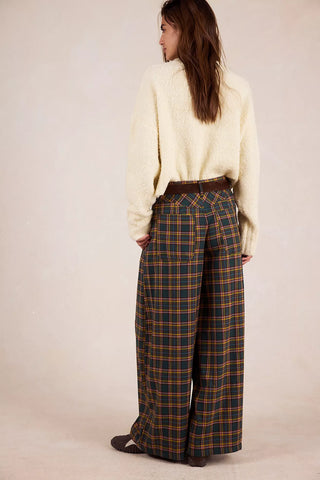 Person wearing a cream sweater and plaid pants on a beige background