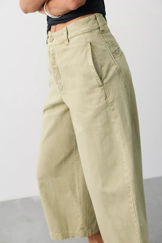 Women wearing green trousers on a neutral background.
