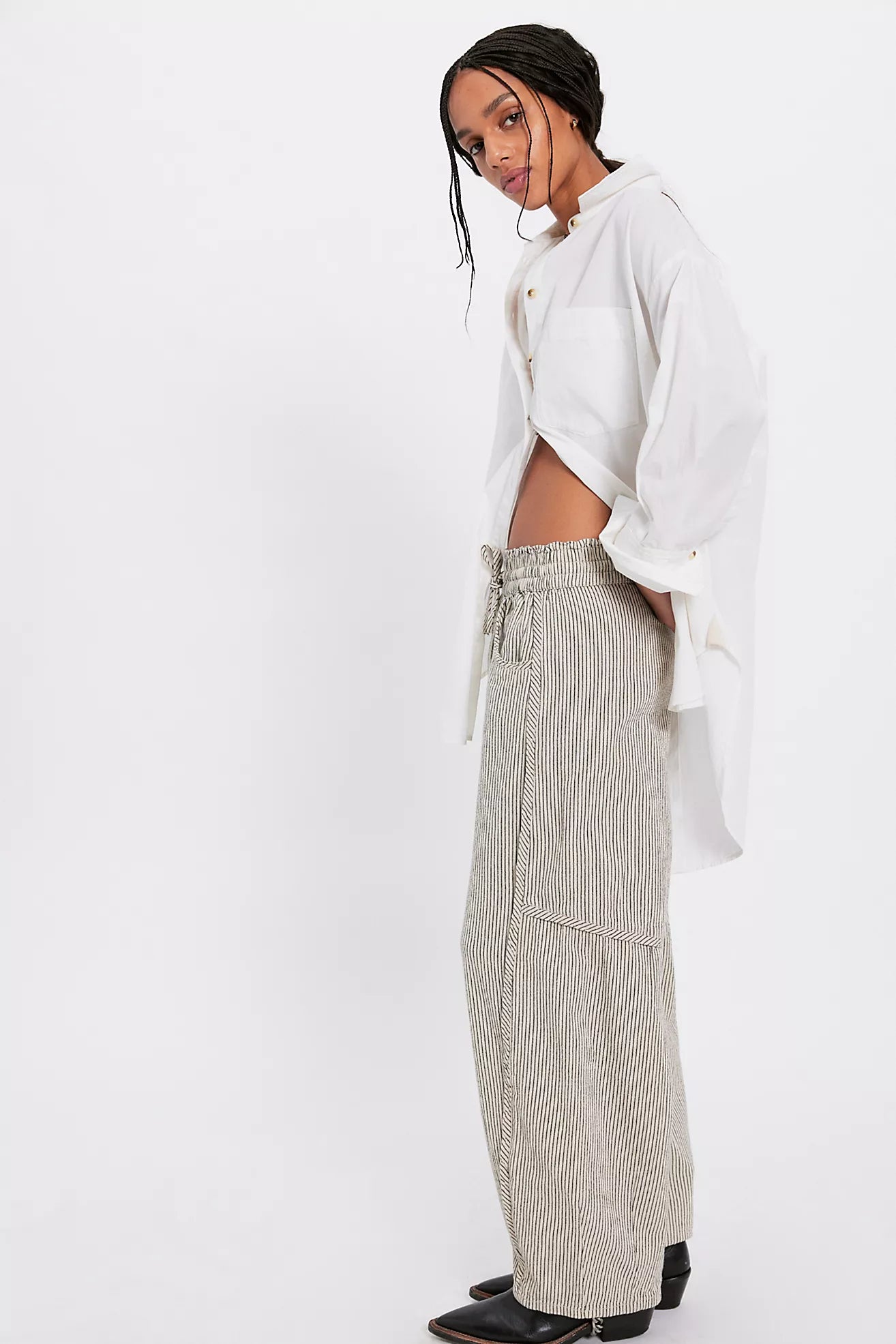 Person wearing a white shirt and beige pants with a belt on a white background