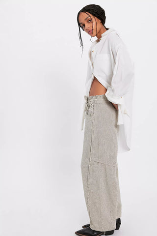 Person wearing a white shirt and beige pants with a belt on a white background
