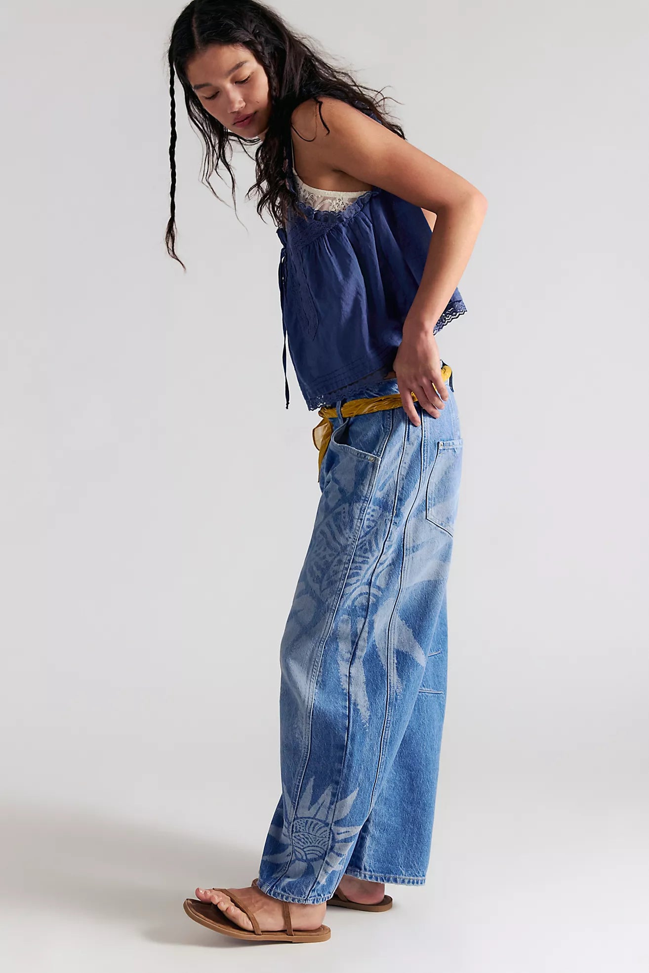 Woman wearing a blue top and wide-leg jeans on a white background