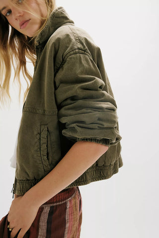 Person wearing a green jacket on a plain background