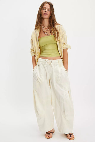Person wearing white wide-leg pants with a green top and yellow scarf on a white background
