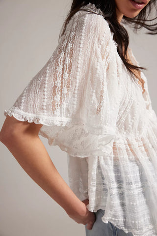 White lace top worn by a person on a plain background