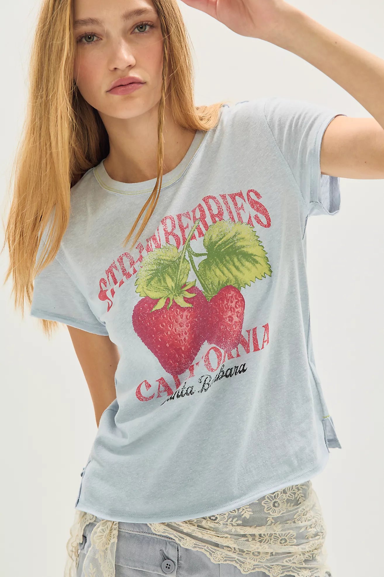 Woman wearing a light blue t-shirt with strawberry and 'California' graphic design.