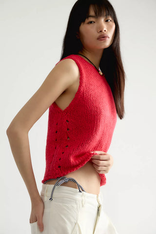 Woman wearing a red knitted sleeveless top on a white background