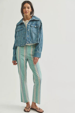 Person wearing a denim jacket and striped pants on a white background