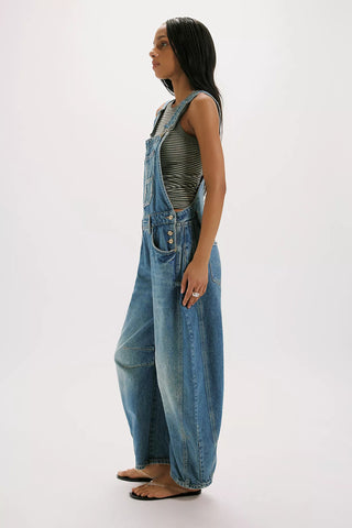 Person wearing blue denim overalls on a white background