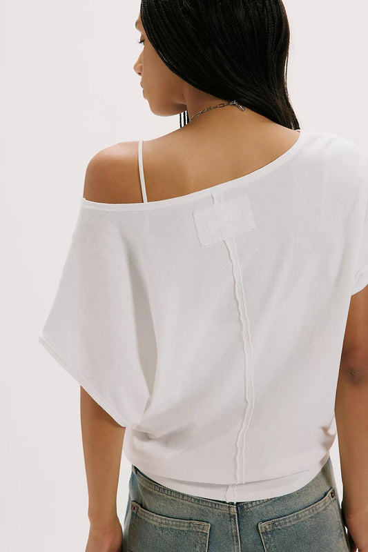 Woman wearing a white off-shoulder top with a plain background