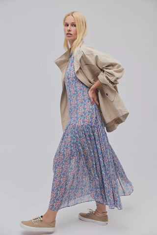 Woman wearing a floral dress with a beige jacket on a white background