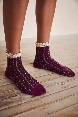 Purple socks with white lace trim worn on a wooden floor