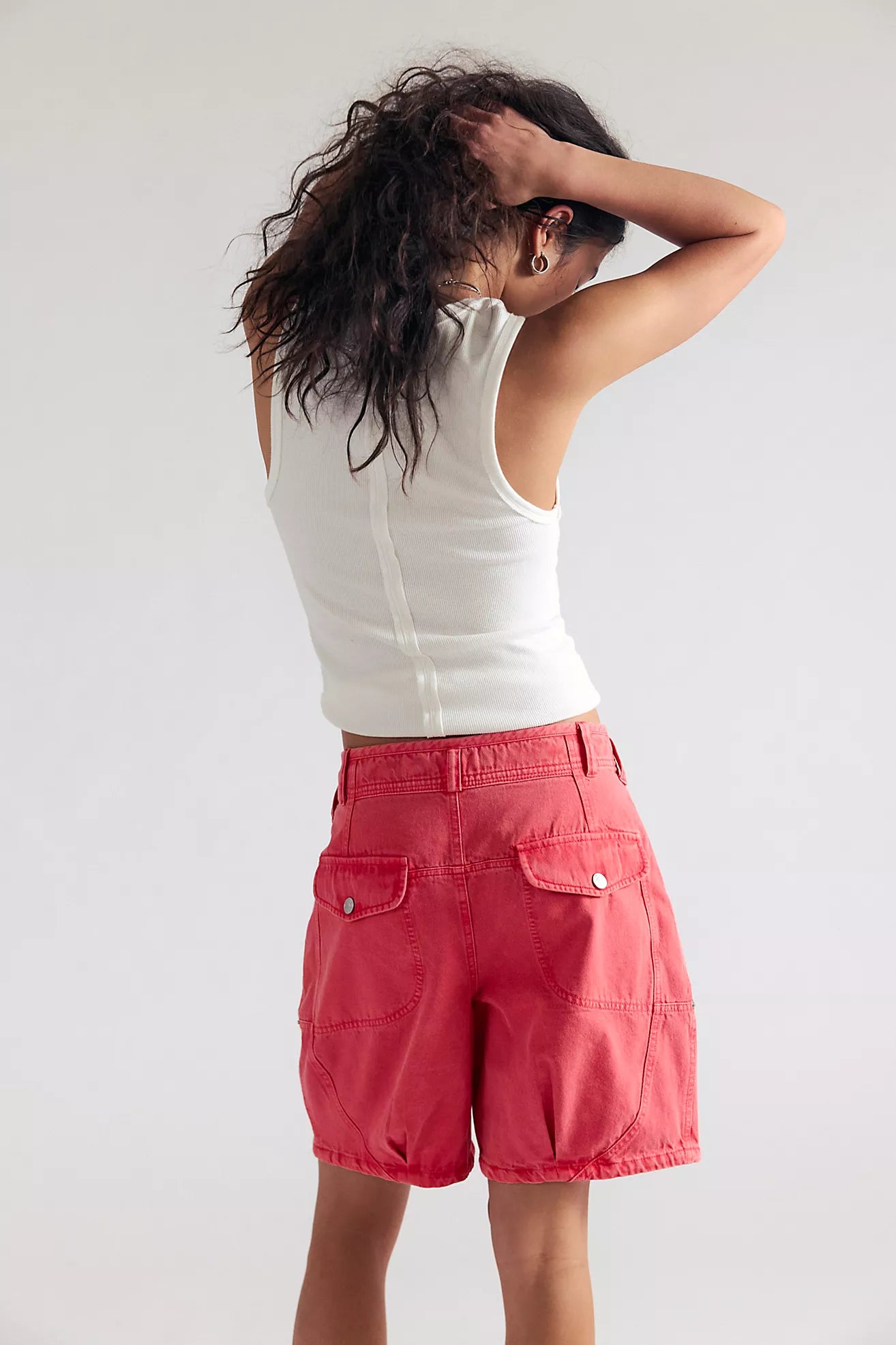 Person wearing a white sleeveless top and red shorts on a plain background