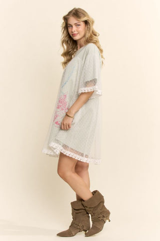 Woman wearing a light dress with lace details and brown boots on a plain background