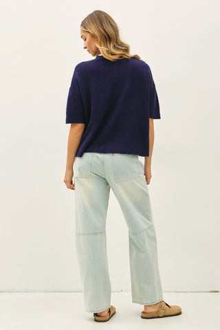 Women wearing a navy short sleeve cardigan against a neutral background. 