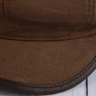Close-up of a brown cap with leather trim on a wooden surface