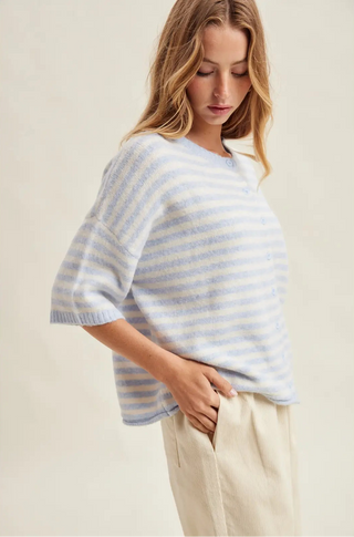 Woman wearing a light blue and white striped sweater against a plain background