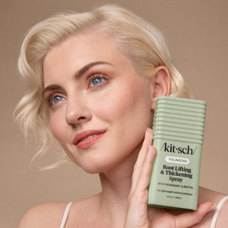 Woman holding a 'kit-sch' hair product with a neutral background