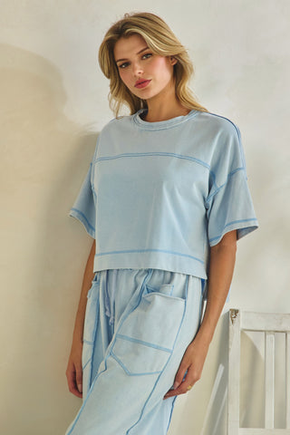 Woman wearing a light blue outfit with thin stripes indoors.