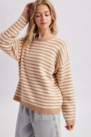 Women wearing a striped beige sweater against a neutral background.