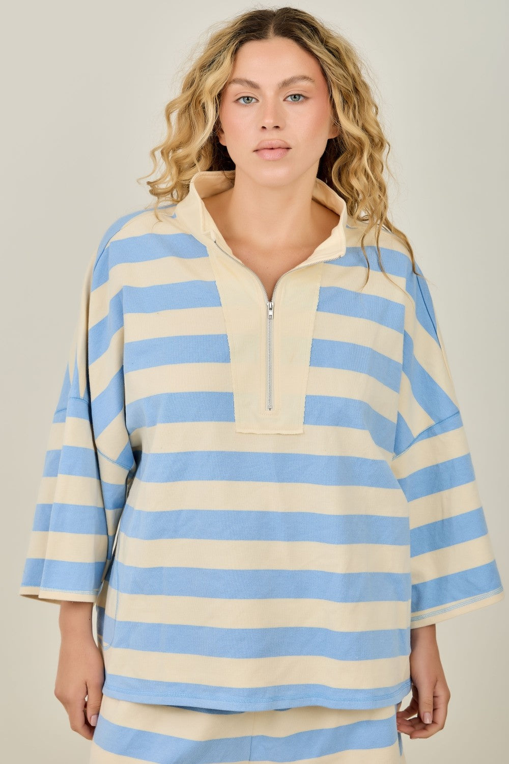 Woman wearing a blue and beige striped shirt against a plain background
