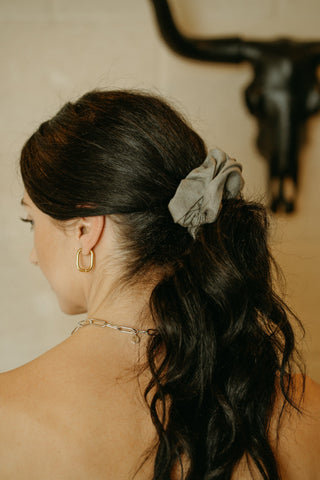 a women wearing hold hoop rectangular shaped earrings