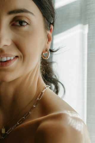 Close-up of a woman wearing a necklace and earrings with a blurred background