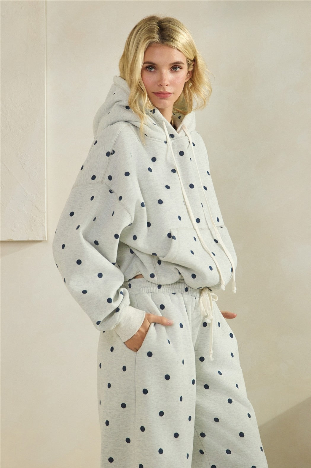Woman wearing a polka dot robe and hoodie set against a plain background