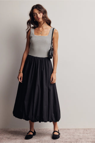 Woman wearing a striped top and black skirt against a plain background