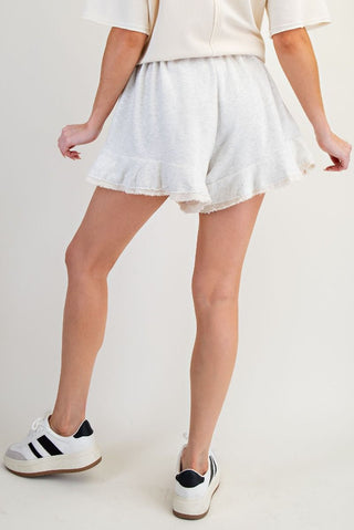 Person wearing light-colored shorts and white sneakers on a plain background