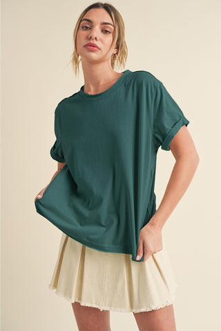 Woman wearing a green oversized t-shirt and beige skirt on a beige background