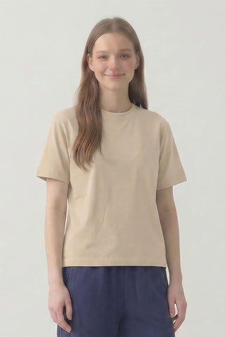 Person wearing a beige t-shirt and blue pants on a plain background