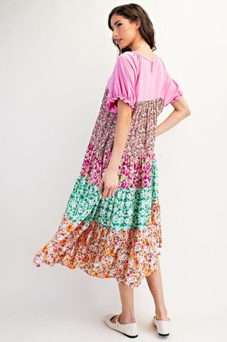 Woman wearing a colorful floral dress with a pink top on a white background