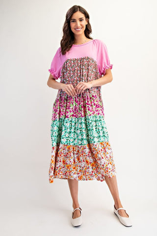 Woman wearing a colorful patterned dress with a pink top on a white background