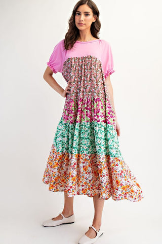 Woman wearing a colorful floral dress over a pink top on a white background