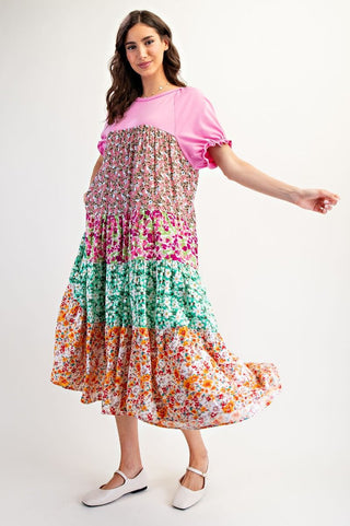 Woman wearing a colorful floral dress with a pink top on a white background