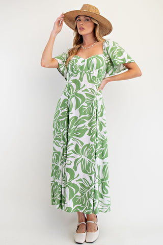 Woman wearing a green leaf-patterned dress and straw hat on a white background