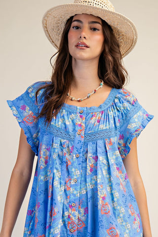 Woman wearing a blue floral dress and straw hat against a neutral background