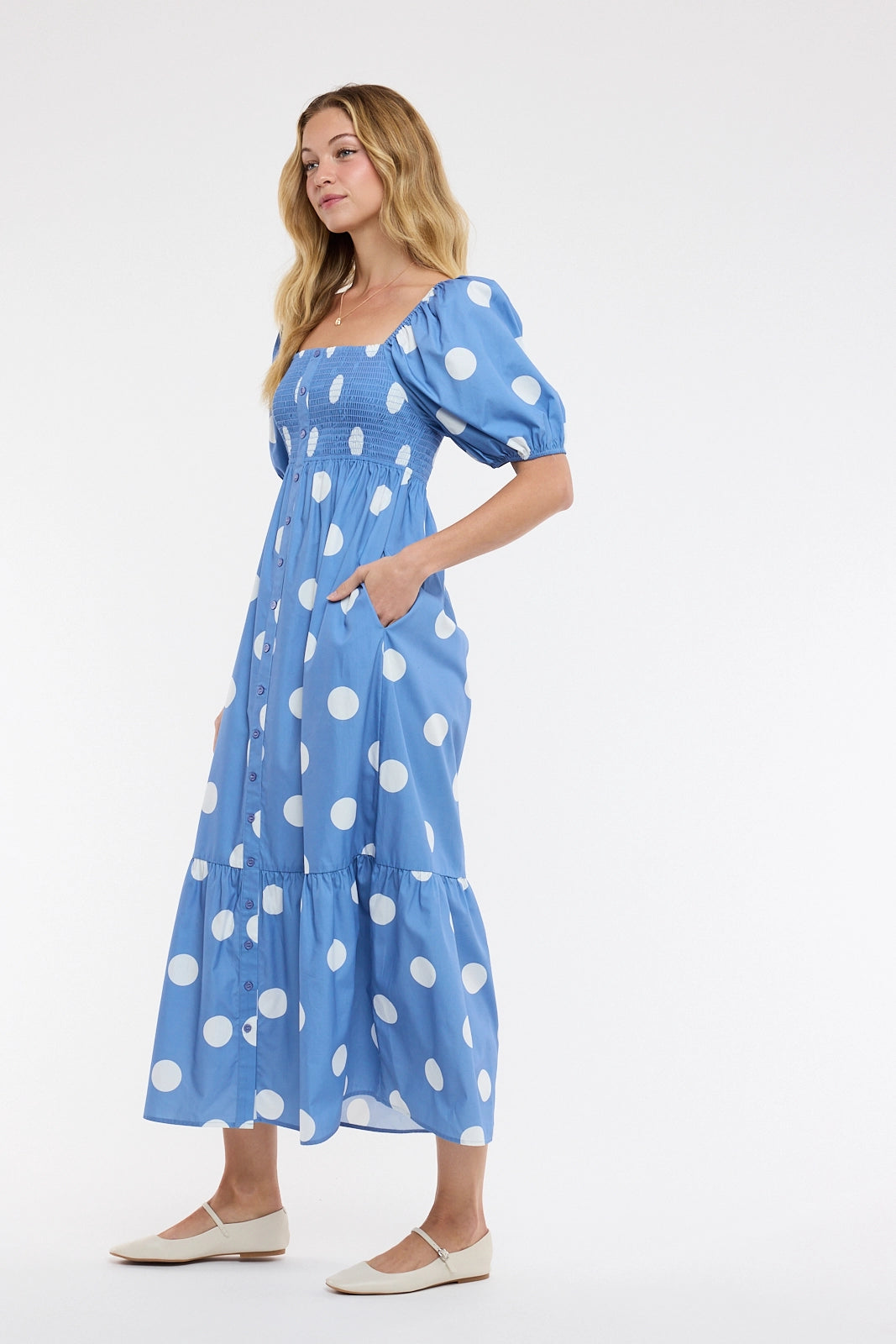 women wearing a blue and white polka dot maxi dress on a white background.