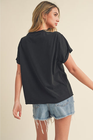 Woman wearing a black oversized t-shirt and denim shorts on a beige background