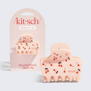 Pink hair clip with cherry design and 'kitsch' packaging on a light gray background