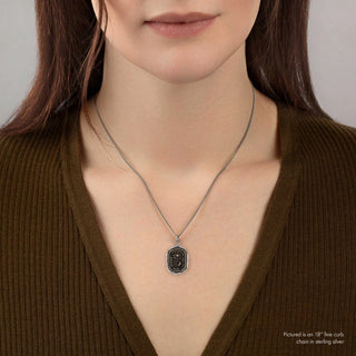 Person wearing a necklace with a pendant on a plain background
