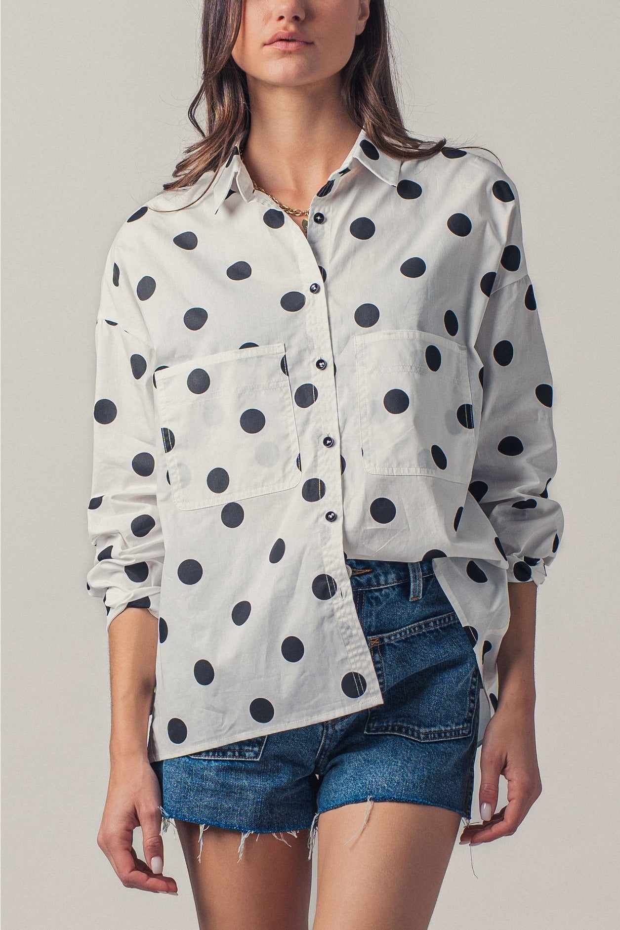 Woman wearing a polka dot shirt and denim shorts on a plain background