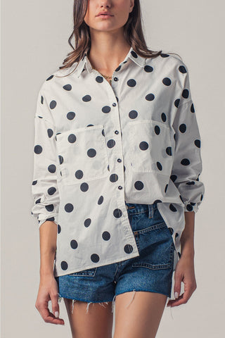 Woman wearing a polka dot shirt and denim shorts on a plain background