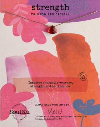 A crimson red cut glass crystal necklace on a display card with abstract pink and orange designs. The necklace is described as inspiring strength and courage.