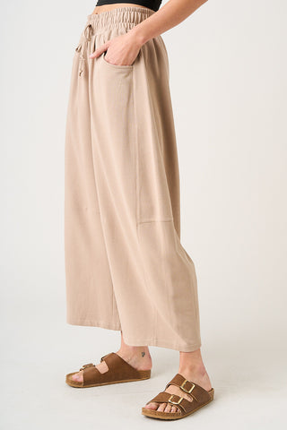 Person wearing beige wide-leg pants with a plain background