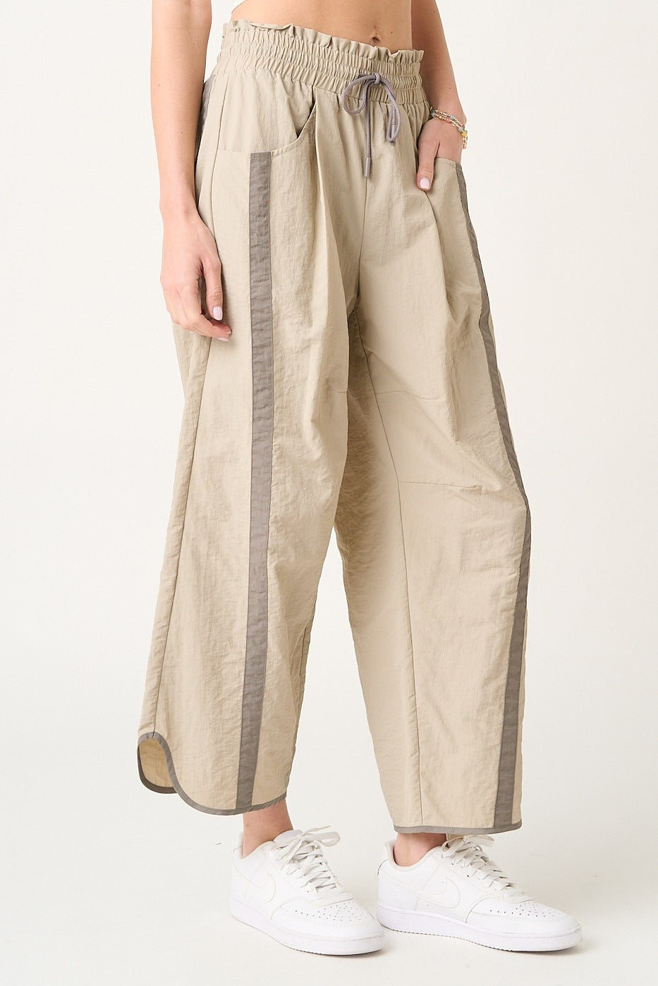 Beige pants with gray stripes worn by a person on a white background