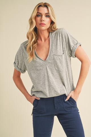 Woman wearing a gray top and blue pants against a beige background