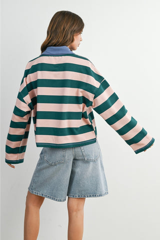 Person wearing a striped sweater and denim shorts on a plain background