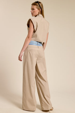 Woman wearing a beige vest and wide-leg pants on a beige background